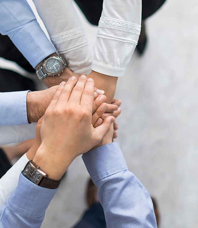 Become a Partner and Team members joining hands together to show unity, teamwork, and collaboration in a professional setting.